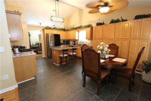 dining space featuring dark tile patterned floors, ceiling fan, sink, and lofted ceiling