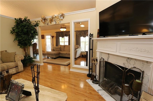 living room with a premium fireplace, crown molding, and light hardwood / wood-style flooring