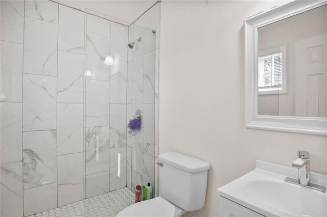 bathroom with toilet, vanity, and tiled shower