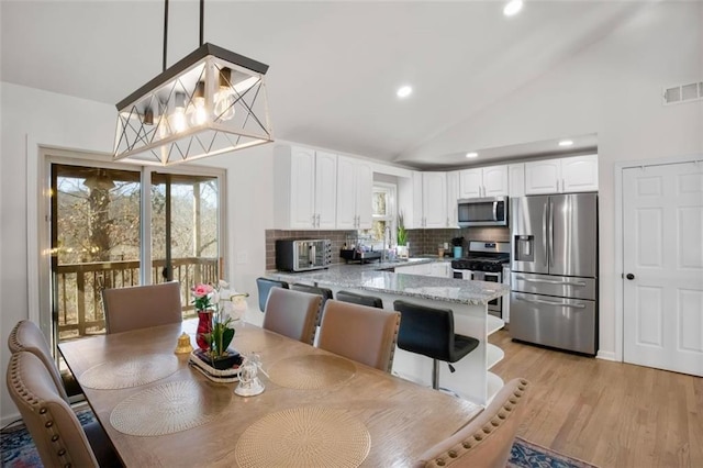 dining room featuring vaulted ceiling, an inviting chandelier, and light hardwood / wood-style flooring