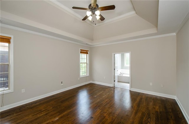 empty room with a raised ceiling, a ceiling fan, baseboards, dark wood-style floors, and ornamental molding