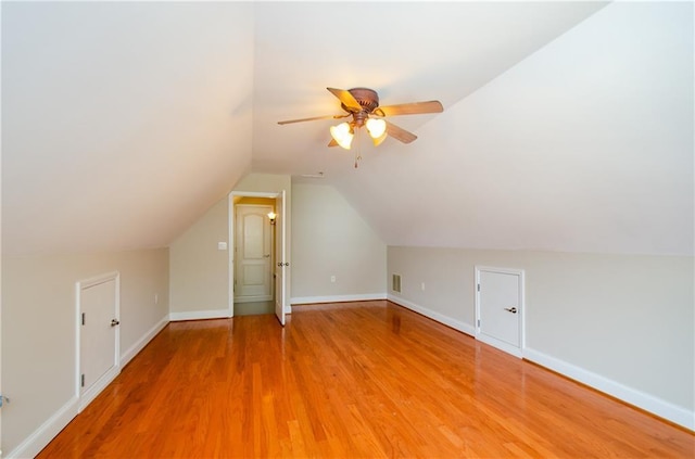 additional living space with light wood-style floors, a ceiling fan, vaulted ceiling, and baseboards