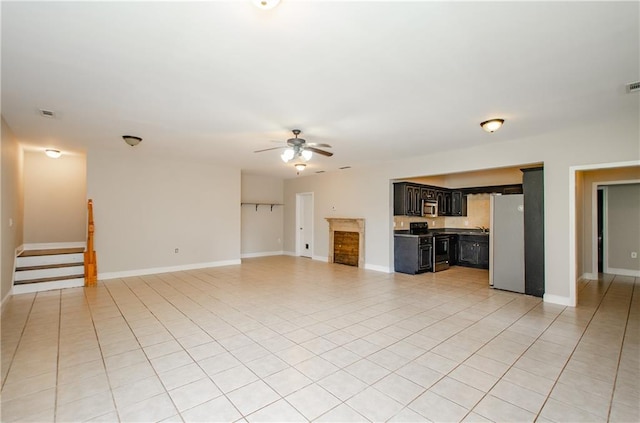 unfurnished living room featuring a ceiling fan, light tile patterned floors, stairs, and baseboards