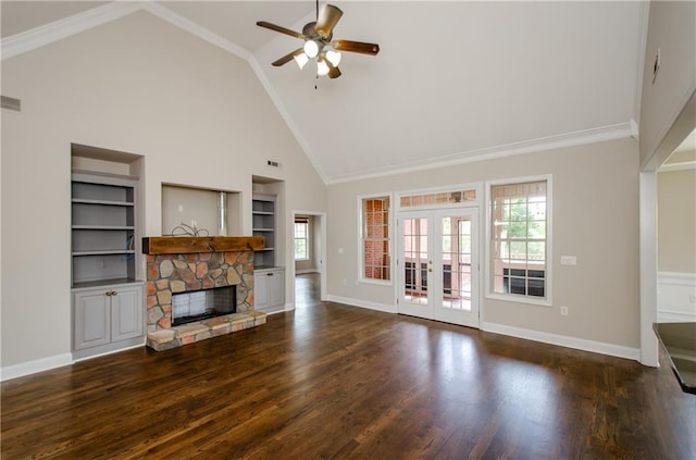 unfurnished living room with high vaulted ceiling, built in shelves, a ceiling fan, a stone fireplace, and baseboards