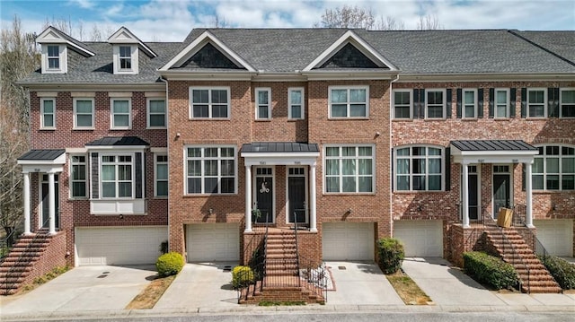 view of property with driveway, a standing seam roof, an attached garage, brick siding, and metal roof