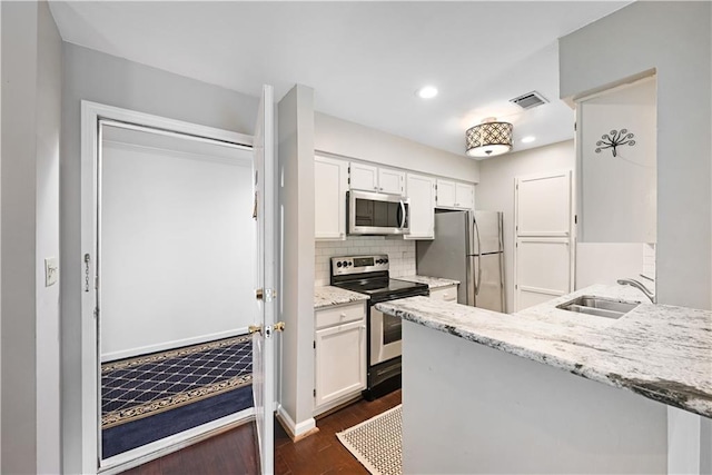 1312 Pine Heights Dr NE, Atlanta, GA 30324 - kitchen featuring appliances with stainless steel finishes, a sink, dark wood finished floors, white cabinetry, and tasteful backsplash