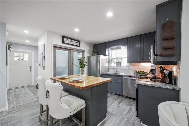 9050 Pine Tree Cir, Gainesville, GA 30506 - kitchen with stainless steel appliances, wooden counters, light wood-type flooring, decorative backsplash, and a breakfast bar area