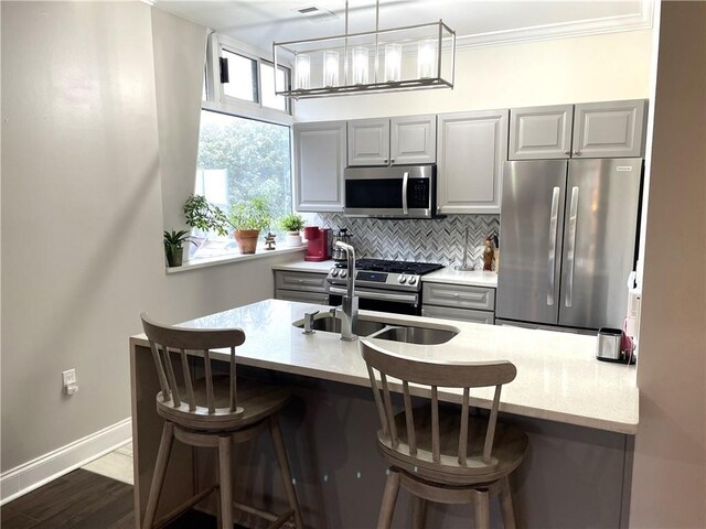 2479 Peachtree Rd NE Unit 105, Atlanta, GA 30305 - kitchen featuring appliances with stainless steel finishes, a sink, gray cabinetry, decorative backsplash, and a breakfast bar area