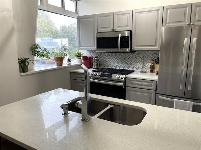 2479 Peachtree Rd NE Unit 105, Atlanta, GA 30305 - kitchen featuring appliances with stainless steel finishes, decorative backsplash, a sink, gray cabinets, and light stone counters