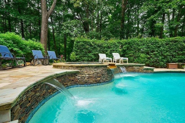 pool with an in ground hot tub and a patio area