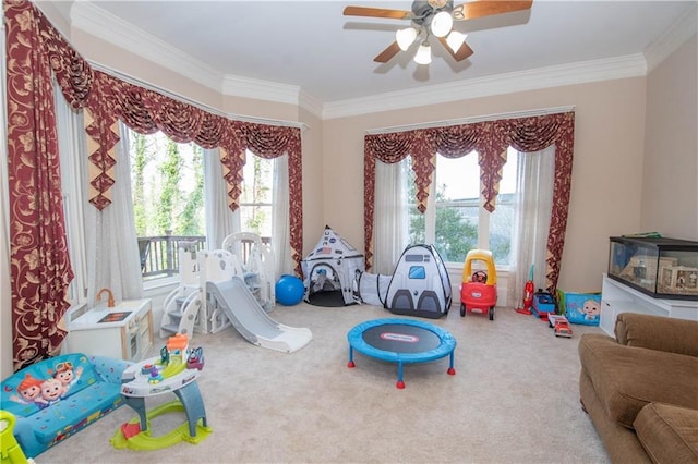 rec room with a ceiling fan, ornamental molding, and carpet flooring
