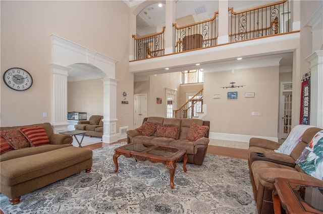 living room with decorative columns, baseboards, a high ceiling, and stairway