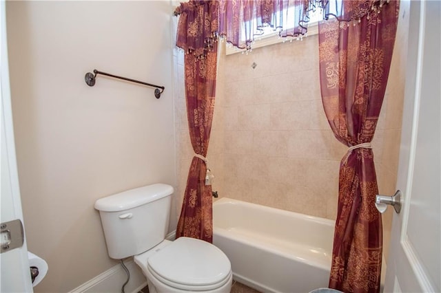 bathroom featuring shower / tub combo, toilet, and baseboards
