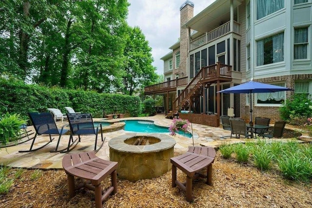 view of pool featuring stairway, a patio area, a pool with connected hot tub, and a fire pit