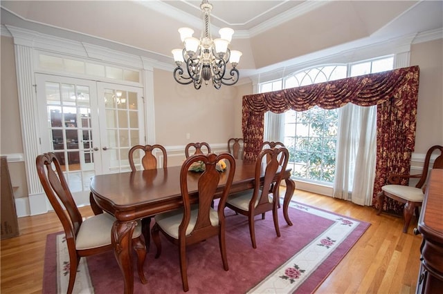 dining space with crown molding, light wood-style flooring, french doors, and a chandelier