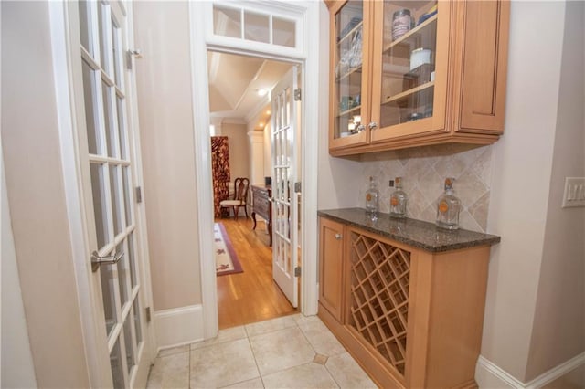 bar featuring baseboards, light tile patterned flooring, ornamental molding, decorative backsplash, and french doors