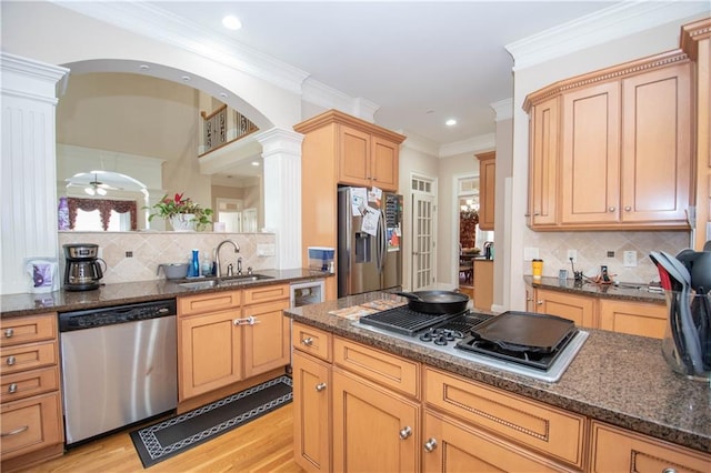 kitchen featuring a sink, dark stone countertops, appliances with stainless steel finishes, and decorative columns