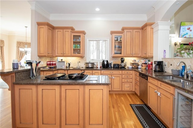 kitchen with a sink, appliances with stainless steel finishes, a peninsula, and light wood finished floors