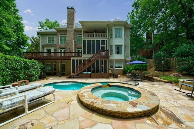view of swimming pool with a deck, a pool with connected hot tub, a patio, fence, and stairs