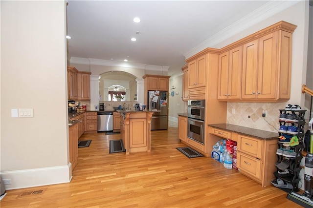 kitchen featuring arched walkways, light wood-style flooring, stainless steel appliances, and ornamental molding