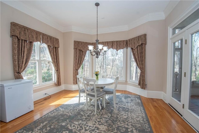 dining area with an inviting chandelier, wood finished floors, baseboards, and ornamental molding