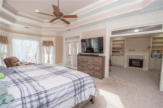 bedroom with visible vents, crown molding, a fireplace with flush hearth, light carpet, and a raised ceiling