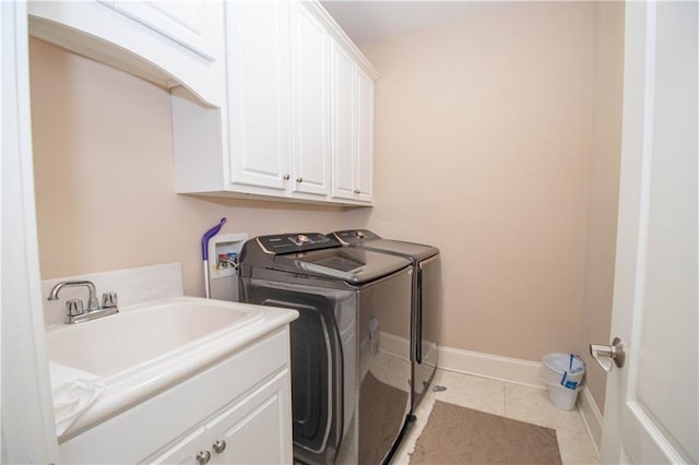 laundry area featuring baseboards, washing machine and dryer, light tile patterned floors, cabinet space, and a sink