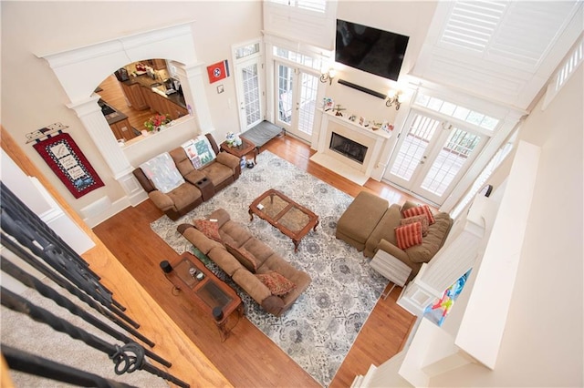 living area featuring a premium fireplace, wood finished floors, ornate columns, and a towering ceiling