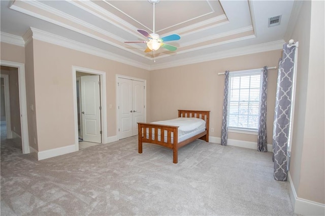 unfurnished bedroom with visible vents, a tray ceiling, carpet floors, crown molding, and baseboards