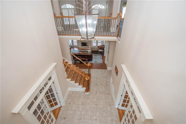 stairs with an inviting chandelier, a high ceiling, and baseboards