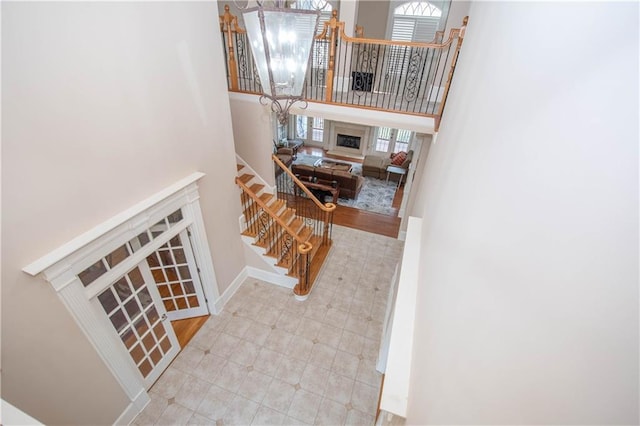 stairway featuring a notable chandelier, baseboards, and a towering ceiling