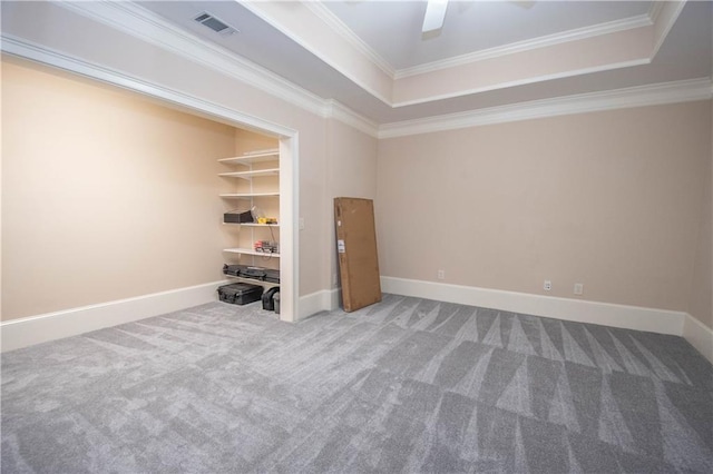 spare room with a tray ceiling, visible vents, and crown molding