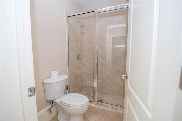 bathroom with toilet, a shower stall, and tile patterned flooring