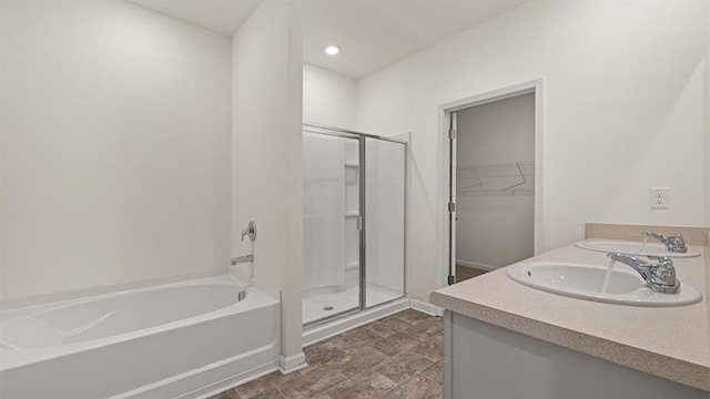 bathroom with a walk in closet, a sink, a shower stall, and a bath