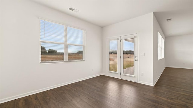 empty room featuring baseboards, visible vents, and dark wood-style flooring