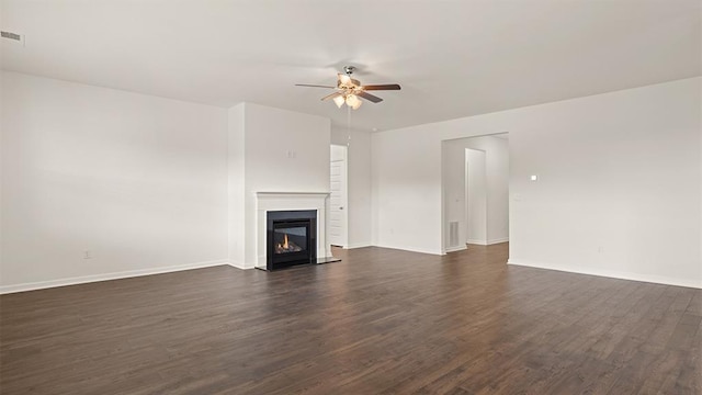 unfurnished living room with visible vents, baseboards, a glass covered fireplace, dark wood-style floors, and ceiling fan