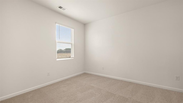 spare room with light carpet, visible vents, and baseboards