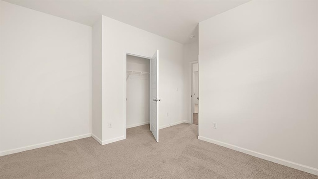 unfurnished bedroom with baseboards, a closet, and light colored carpet