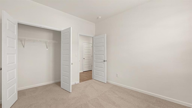 unfurnished bedroom with carpet floors, a closet, and baseboards