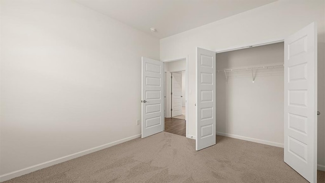 unfurnished bedroom featuring carpet, baseboards, and a closet