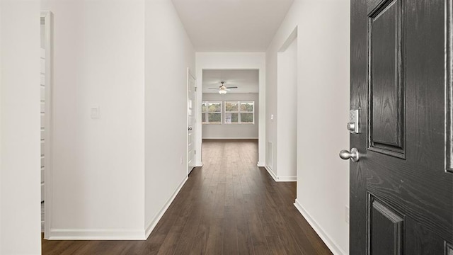 corridor with dark wood-style floors and baseboards