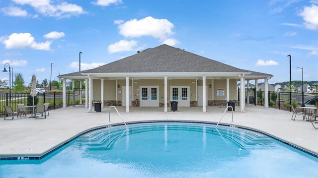 community pool featuring a patio area, fence, and french doors