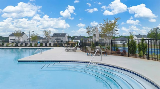 pool with a patio area, fence, and a residential view