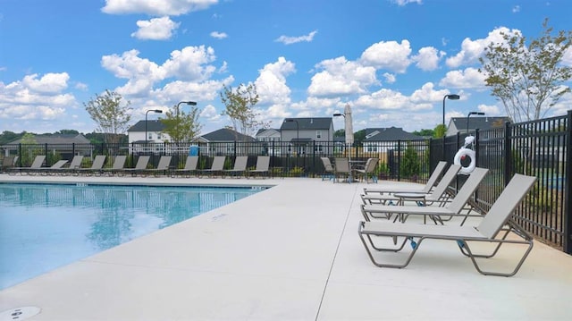 view of swimming pool featuring a residential view, a patio area, and fence