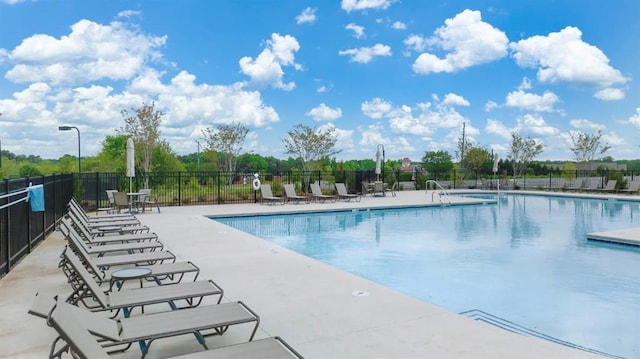 pool with a patio area and fence