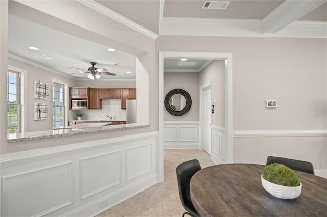 kitchen featuring a decorative wall, a wainscoted wall, visible vents, freestanding refrigerator, and crown molding