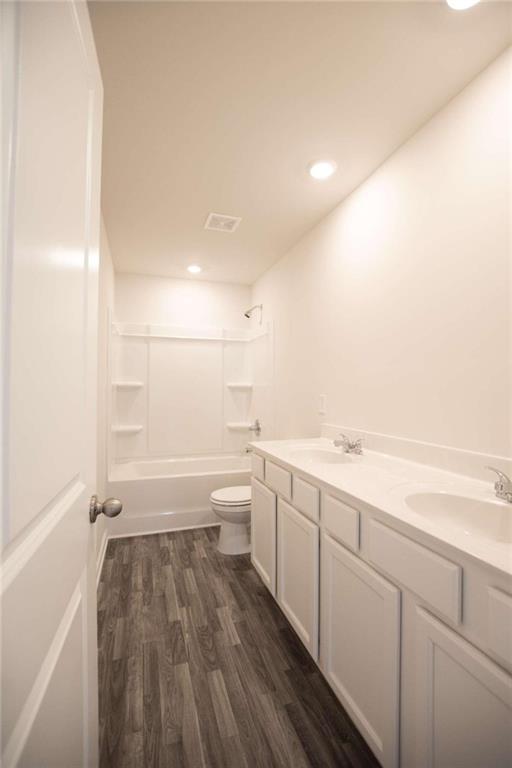 full bathroom featuring toilet, vanity, wood-type flooring, and  shower combination