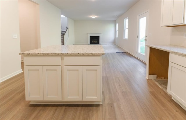 530 River Run Dr, Dallas, GA 30132 - kitchen featuring light wood-style floors, a fireplace, white cabinetry, light stone countertops, and baseboards