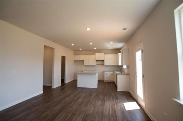 kitchen with white cabinetry, a center island, and dark wood-type flooring