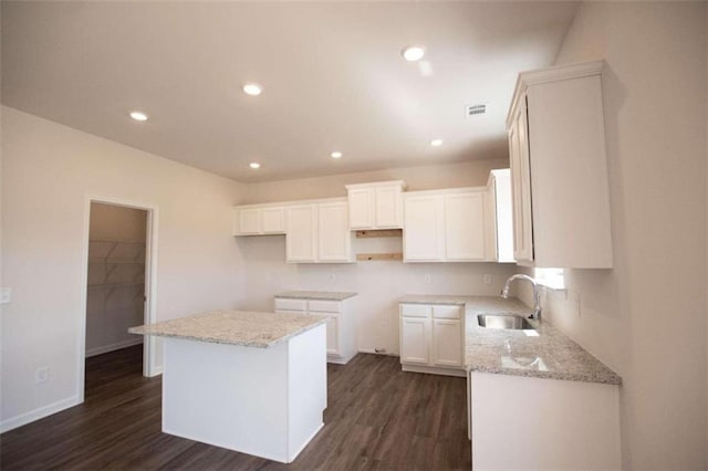 kitchen with dark wood-type flooring, white cabinets, a center island, and sink